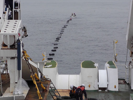 2013年7月9日　敷設船から繰り出したケーブルに浮輪を付けて、小型作業船が陸まで牽引していきます。