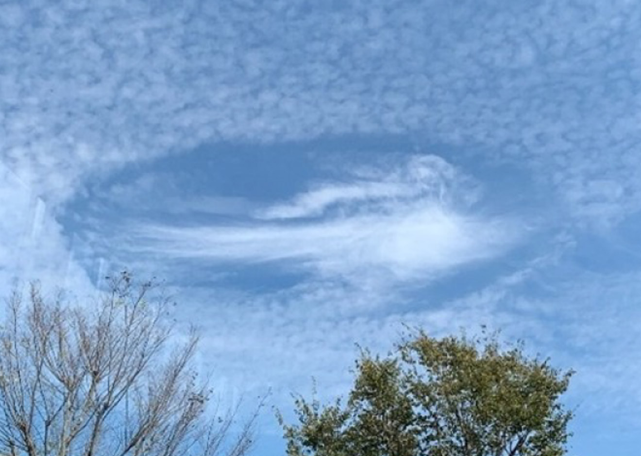 空一面に広がる雲の中央に、円形の大きな穴があいたように見える「穴あき雲」。周囲には細かい雲が広がり、穴の部分は青空が見えている。：写真